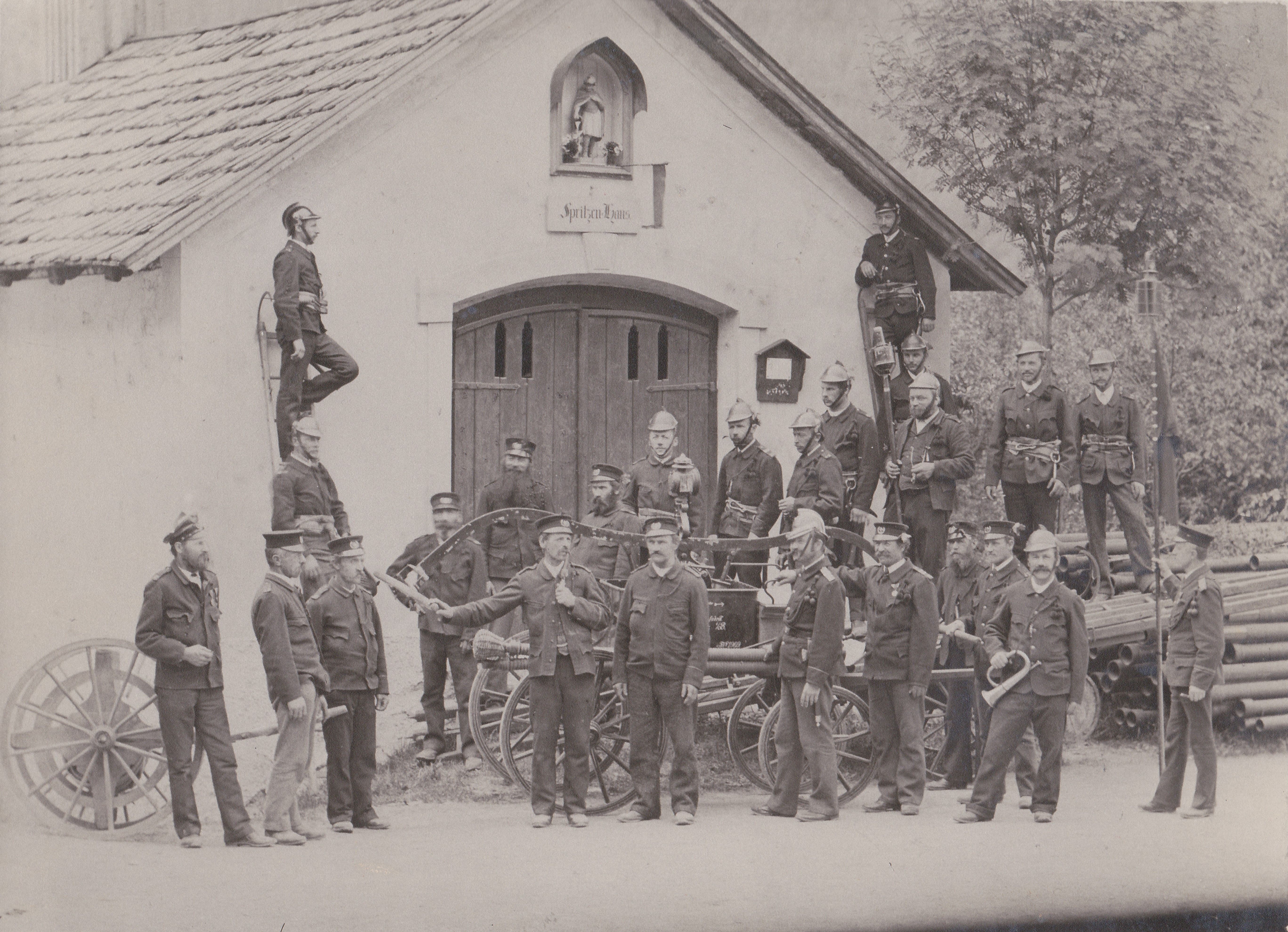 ein schwarz-weiß Foto der Feuerwehrmannschaft vor dem Spritzenhaus