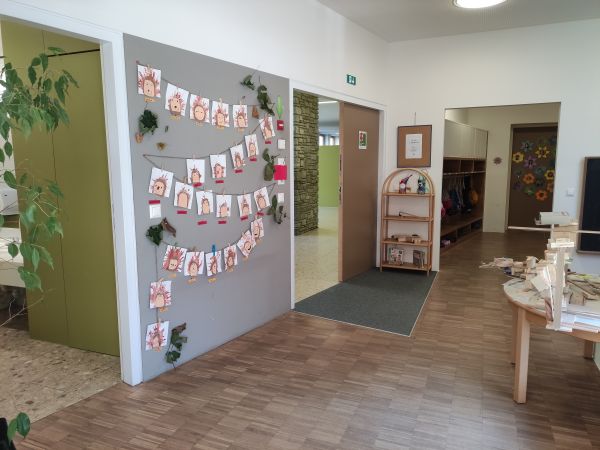 Eingangsbereich des Kindergartens, links hängen Kinderzeichnungen auf einer grauen Wand