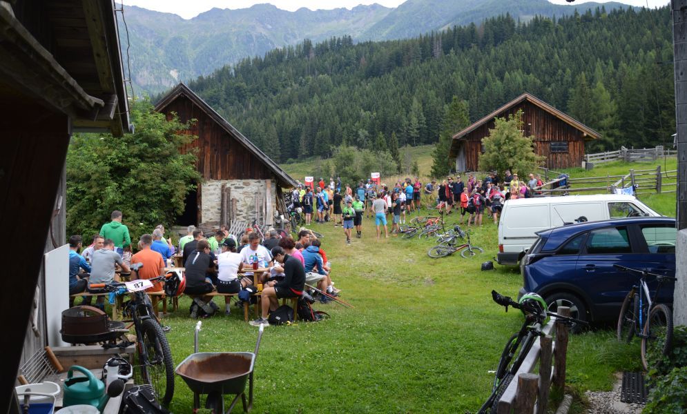 Teilnehmer der Rabantalm Trophy 2025 versammeln sich mit Fahrrädern vor Almhütten, im Hintergrund Berge und Wald