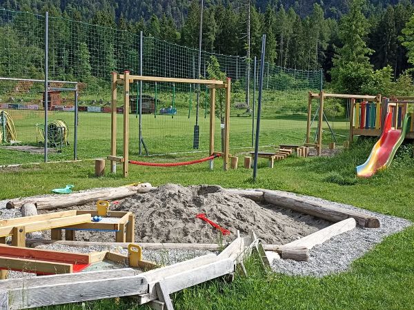 diverse Spielgeräte für Kinder darunter befinden sich unter anderem eine Sandspielkiste und eine Rutsche