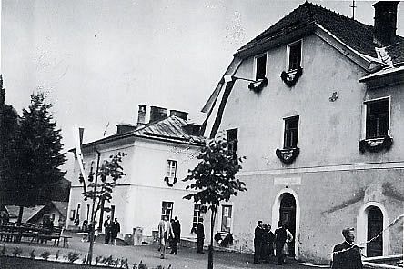 Schwarz-Weiß-Foto von historischen Gebäuden mit Menschen davor in schlichter Architektur.