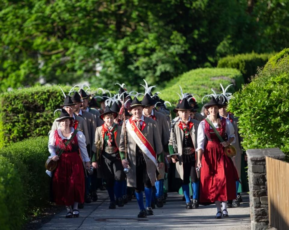 Eine Gruppe von Menschen in traditionellen Trachten, mit Hüten mit Federn